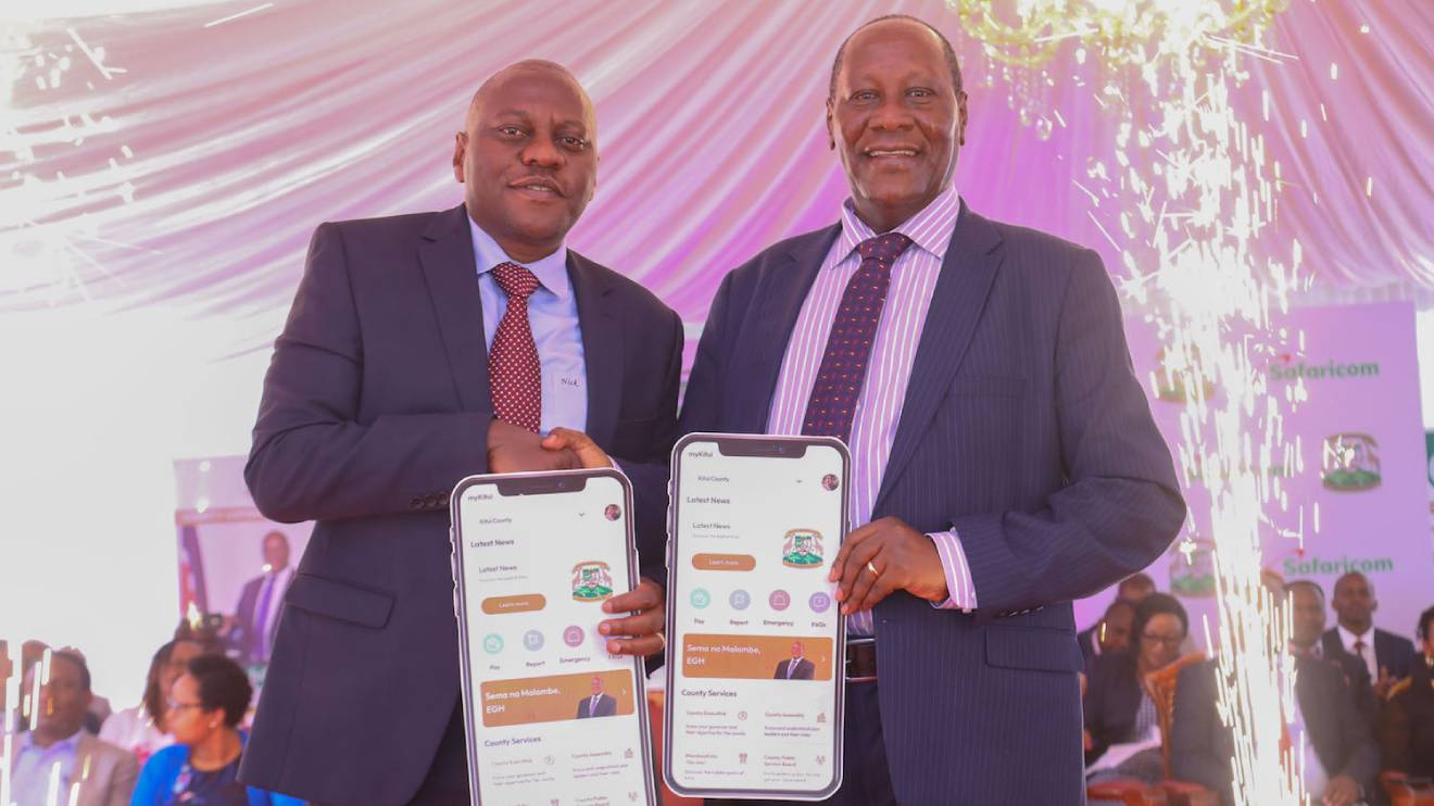 From Left, Nicholas Mulila and Julius Malombe holding dummy phone apps of the new myKutuicounty App launched at the county headquarters in Kitui County. PHOTO/SAFARICOM
